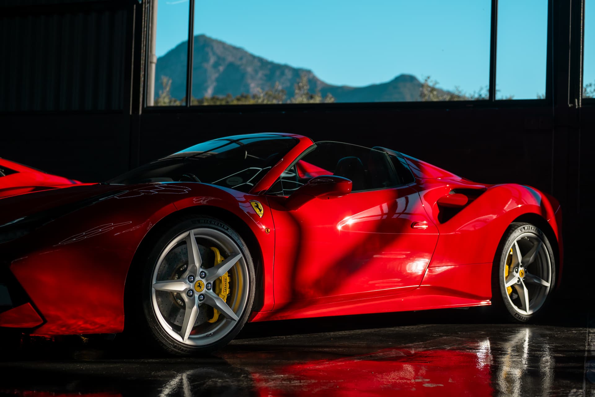 Luxcape Auto facility — two red Ferraris in the showroom with mountain backdrop